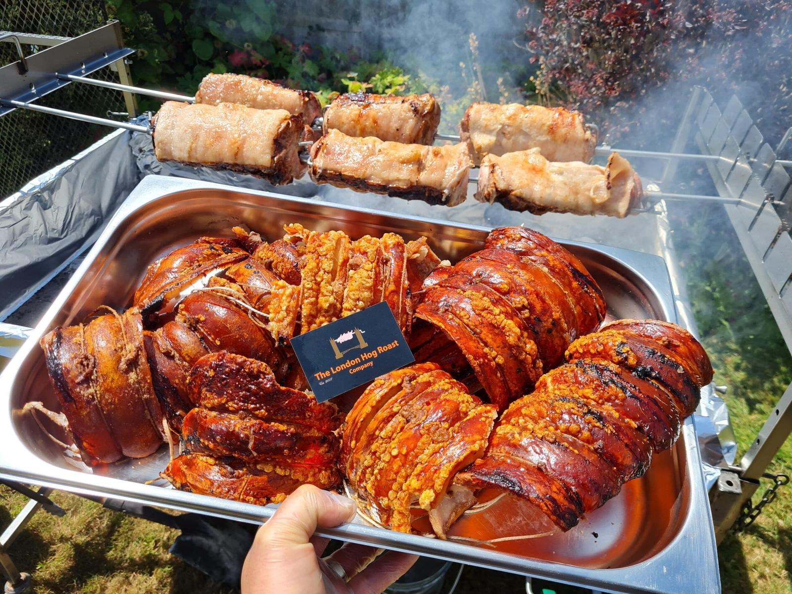 A tray of carved pork and crackling with a London Hog Roast Company card