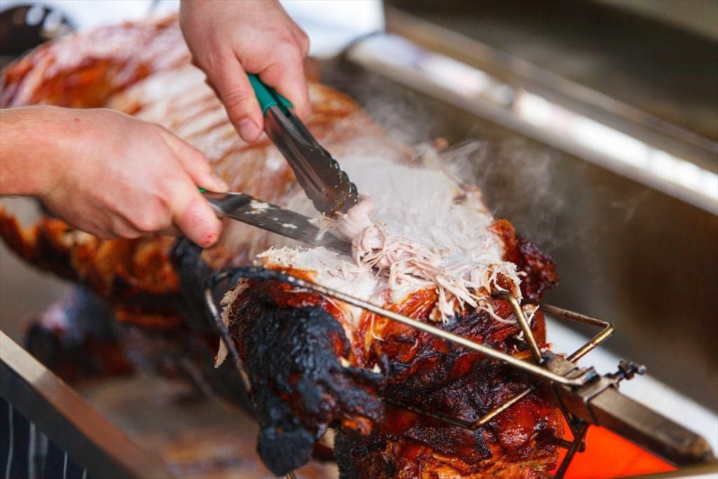 Chef pulling roast pork apart with tongs